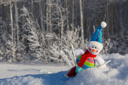 A smiling, happy snowman on skis surrounded by a winter landscapeの写真素材