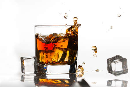 Whiskey on the rocks splashed by ice cubesの写真素材