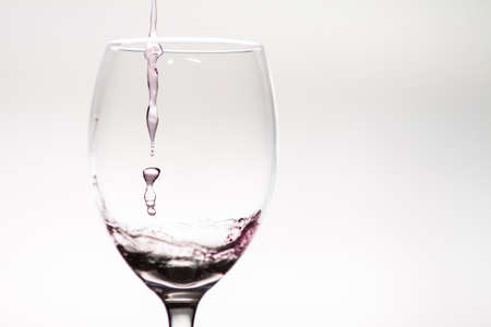 Drop of wine falling into a wineglassの写真素材