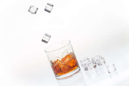 Whiskey on the rocks splashed by falling ice cubesの写真素材