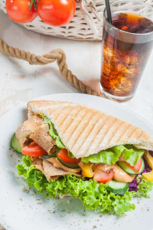 Kebab in grilled pita bread next to cold beverageの写真素材
