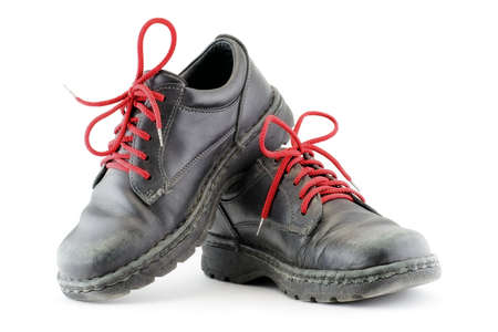 Worn black shoes with red laces over white background