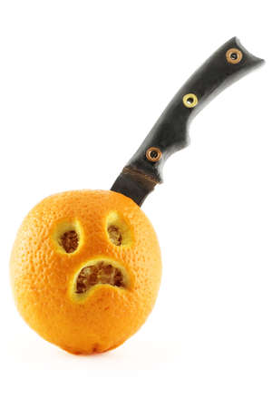 Knife cutting an orange with sad faceの写真素材