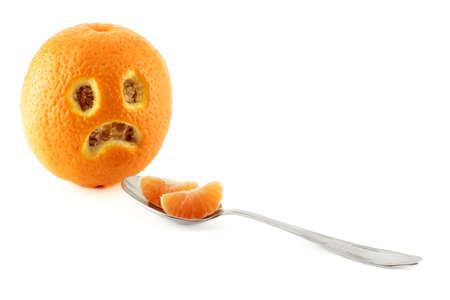 Sad faced orange and a spoon with two mandarin clovesの写真素材