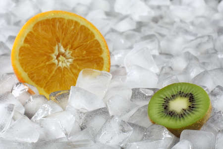 Kiwi and orange halves between ice cubesの写真素材