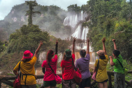 Women and men taking pictures with the thee Lor Sue  waterfall  in Umphang Wildlife Sanctuary,Thailandの写真素材