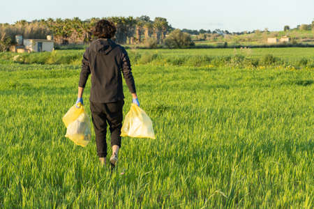 man on his back with plastic bags looking for litter from nature