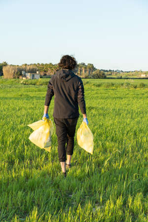 man on his back with plastic bags looking for litter from nature