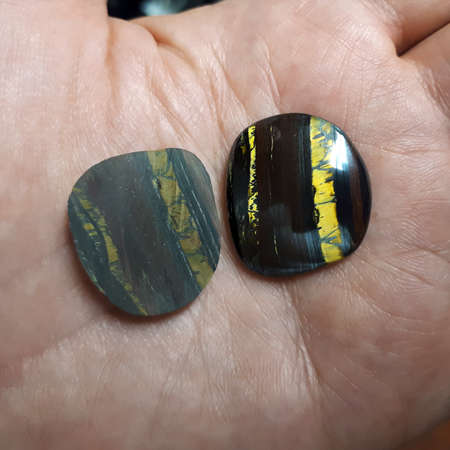 Two pieces of tiger eye on palm - one crude and one after manual processingの写真素材