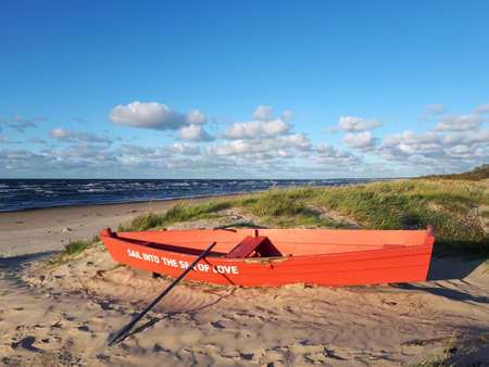 Red boat with the inscription "Sail into the sea of love" on the Baltic Sea coastの写真素材