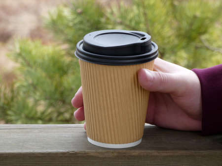 Cardboard cup for hot drinks (coffee, tea, chocolate) in the hand of a young man against the...