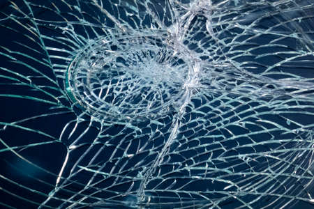Broken car windshield close-up, round dent, many cracks