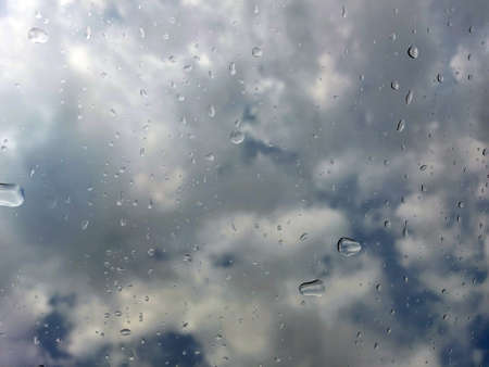 Raindrops on glass on a blurred background of cloudsの写真素材