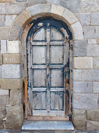 Very old door in a stone wall painted with peeling blue paintの写真素材