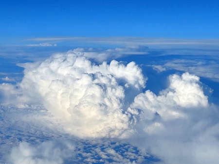 View from an airplane porthole to the beautiful white clouds and clear blue skyの写真素材