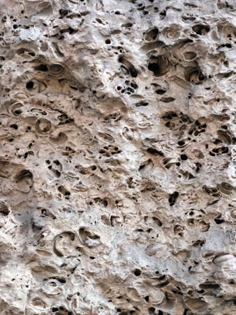 Fragment of a wall of an old house made of sandstone close-up. The texture of a very old stone,...
