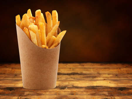 french fries in a paper basket on wooden tableの写真素材