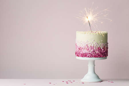 Birthday cake with pink sprinkles and sparklerの写真素材