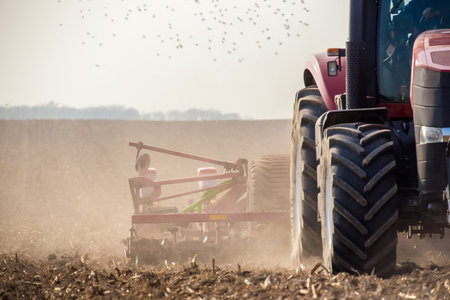 Tractor plowing the field with seedbed cultivator at springの写真素材