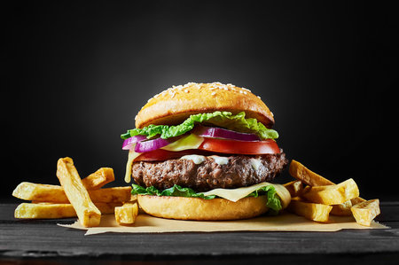 Craft beef burger and french fries on wooden table isolated on black background.の写真素材