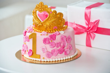 Wedding cake decorated with pink roses and gold crown on topの写真素材