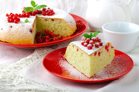 Cake with red currant on a red plate on a white backgroundの写真素材
