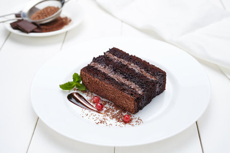 Chocolate cake with berries and mint on a white wooden table.の写真素材