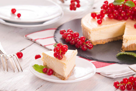 Cheesecake with fresh red currant on white wooden background.の写真素材
