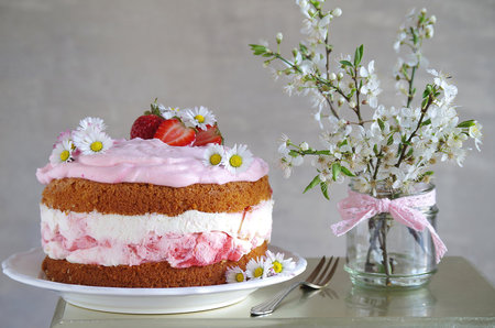 Strawberry cake with cream and flowers in a glass vaseの写真素材