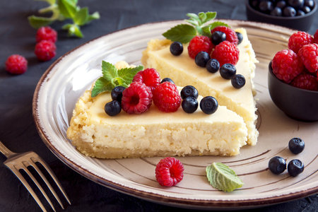 Cheesecake with fresh raspberries and blueberries on a plateの写真素材