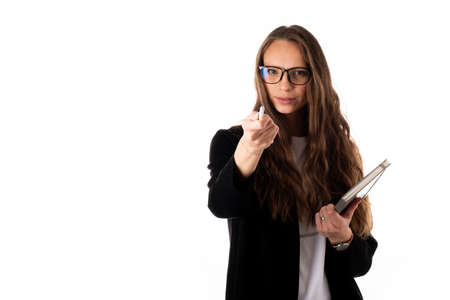 Young cheerful business woman in black coat on a white background holding a pen, laptop or notebook