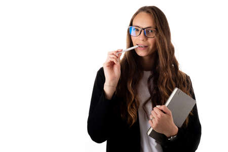 Young cheerful business woman in black coat on a white background holding a pen, laptop or notebook