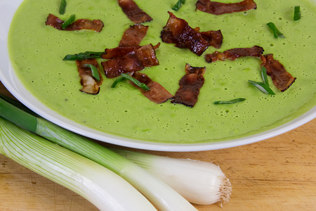 Creamy green pea soup with roasted bacon and onionの写真素材