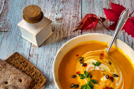 Pumpkin soup with roasted seeds and the sour cream on the wooden tableの写真素材