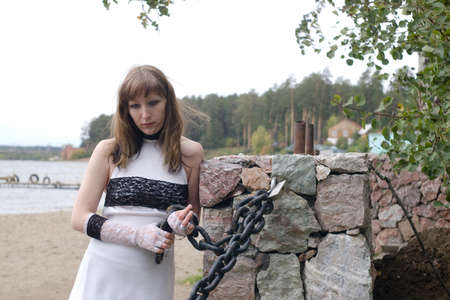 young women in white dress with black lace play with big chainの写真素材