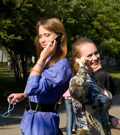 Beaty young women talks from cellular phones on the parkの写真素材