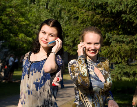 Beaty young women talks from cellular phones on the parkの写真素材