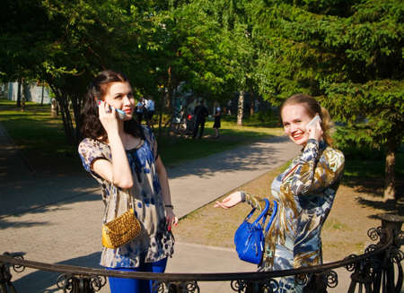 Beaty young women talks from cellular phones on the parkの写真素材