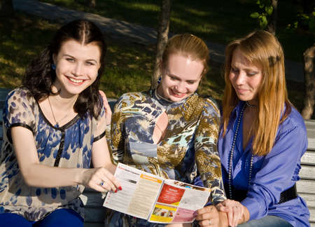 Three girls discuss magazine on the branchの写真素材