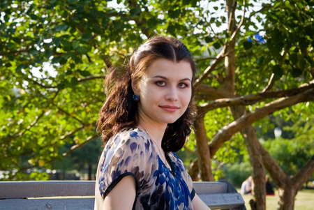 Portret of the young woman on the branch in the parkの写真素材