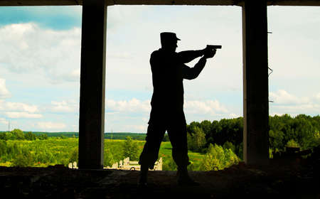 The Contour of soldier with a gun opposite to window with peace landscape.の写真素材
