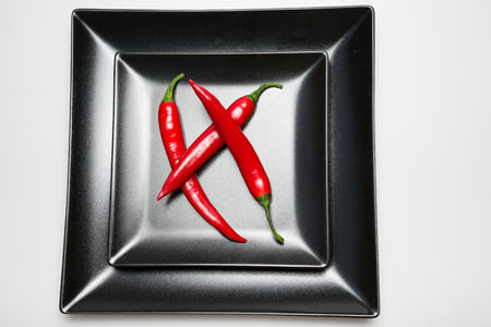 Red hot chilli peppers on a black plateの写真素材