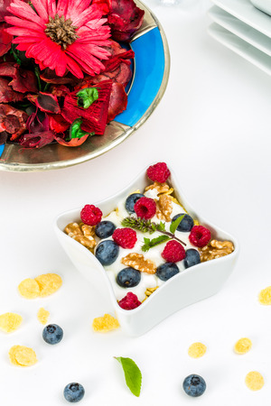 Corn flakes with yoghurt, honey, walnuts raspberries and blueberries. Concept of healthy food.の写真素材