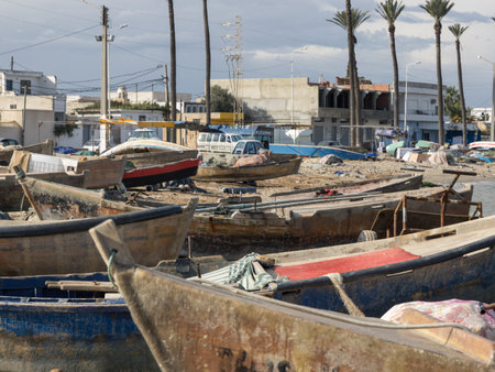Weathered wooden fishing boats rest on the sandy shore, waiting for their next journey into the...
