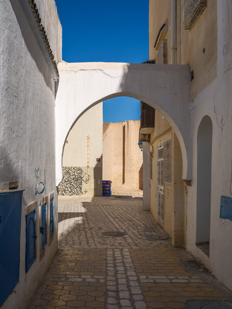 A sunlit stroll through the narrow alleys of Kairouanâs UNESCO-listed Medina. The historic architecture and vibrant blue doors capture the authentic spirit and timeless charm of Tunisiaâs spiritual heart under a clear winter sky.の写真素材