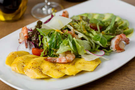 restaurant dish with shrimp and mango in a white plateの写真素材