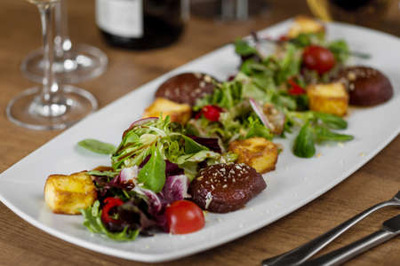 closeup dish with vegetables, meat, crackers, sprinkled with almond crumb on a wooden tableの写真素材