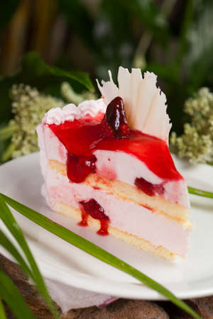 piece of cake of a souffle and biscuit, covered with whipped cream, strawberries and jam on a white...