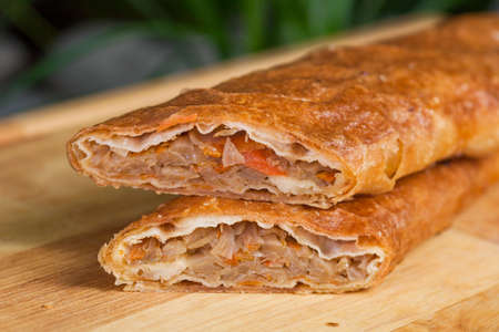 baking of unleavened dough stuffed with cabbage and dried apricots on a wooden boardの写真素材