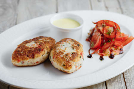 Chicken cutlet with tomato on a white plateの写真素材